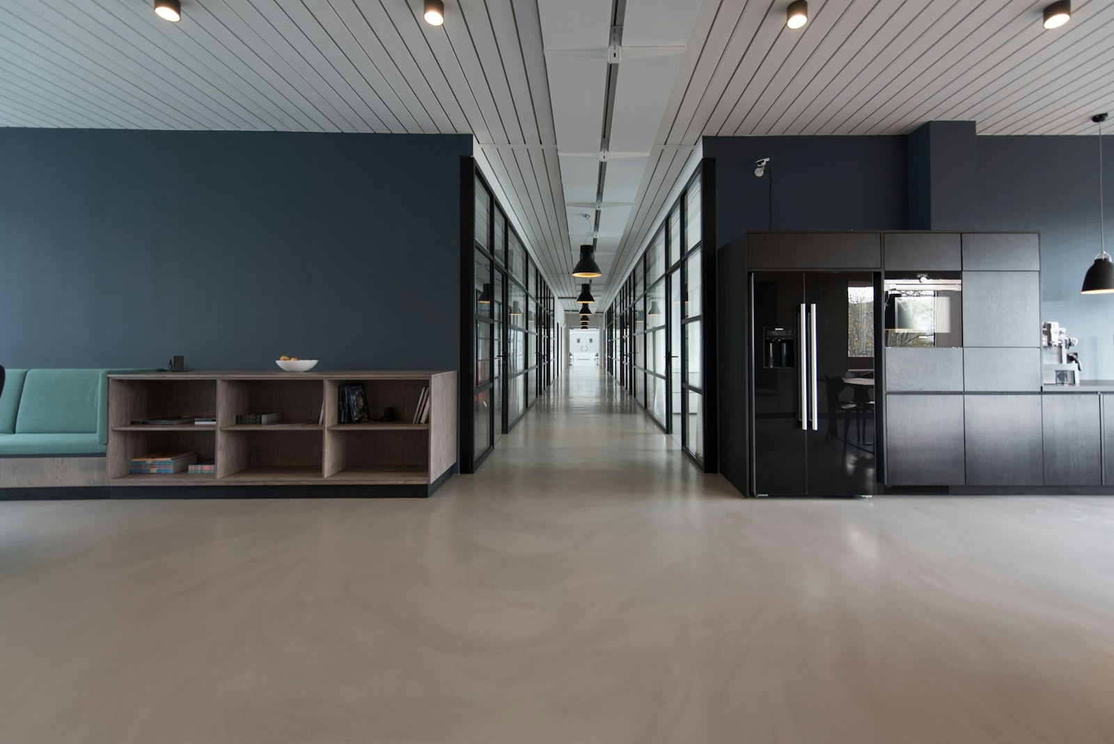 Open-plan office with long desks and several people working at their computers.
